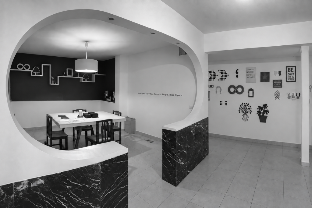 Black-and-white studio interior with a curved opening, meeting table and wall-mounted design samples